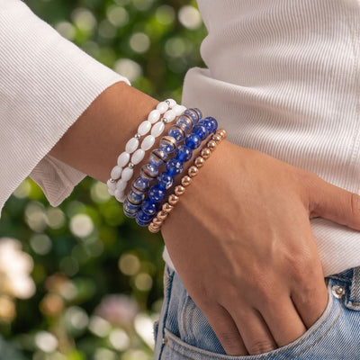 NOGU Made to Pair Sapphire Firefly bracelet stack with deep blue glass beads, white pearl-style beads, and rose gold-toned accents.