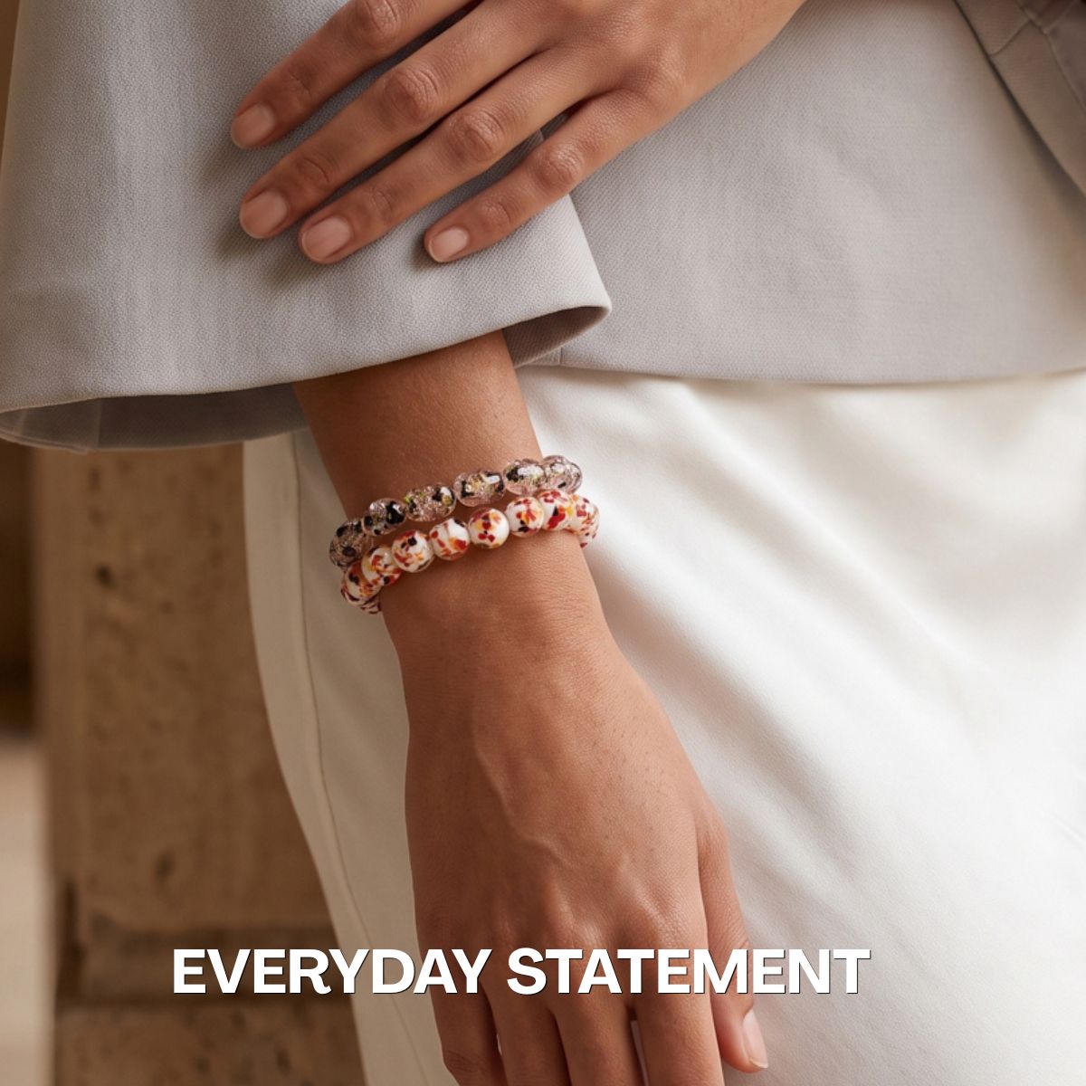 Stacked beaded stretch bracelets with clear crystal and white floral-patterned beads, styled on a wrist.