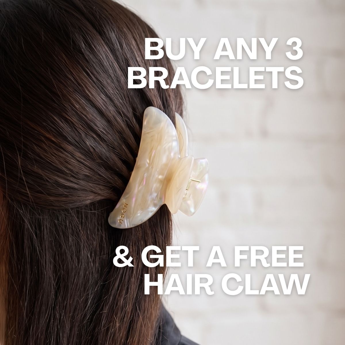 NOGU pearlescent ivory butterfly hair claw worn in dark brown hair, promoting a free claw with any three bracelets.