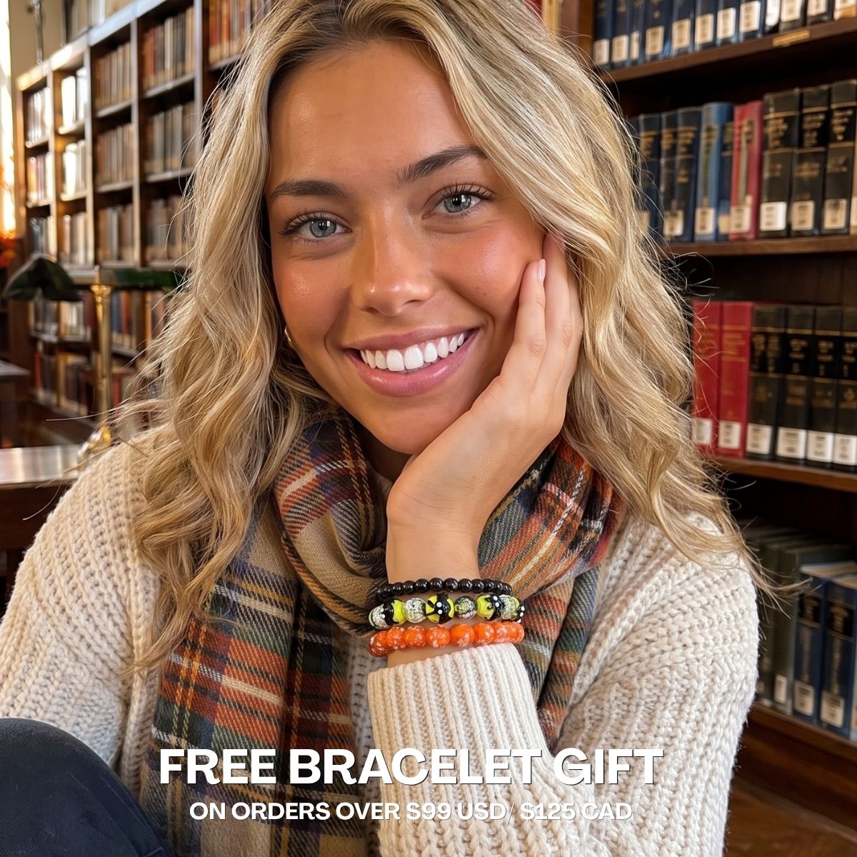 Model wearing stacked black, yellow, and orange beaded bracelets with a plaid scarf in a library.