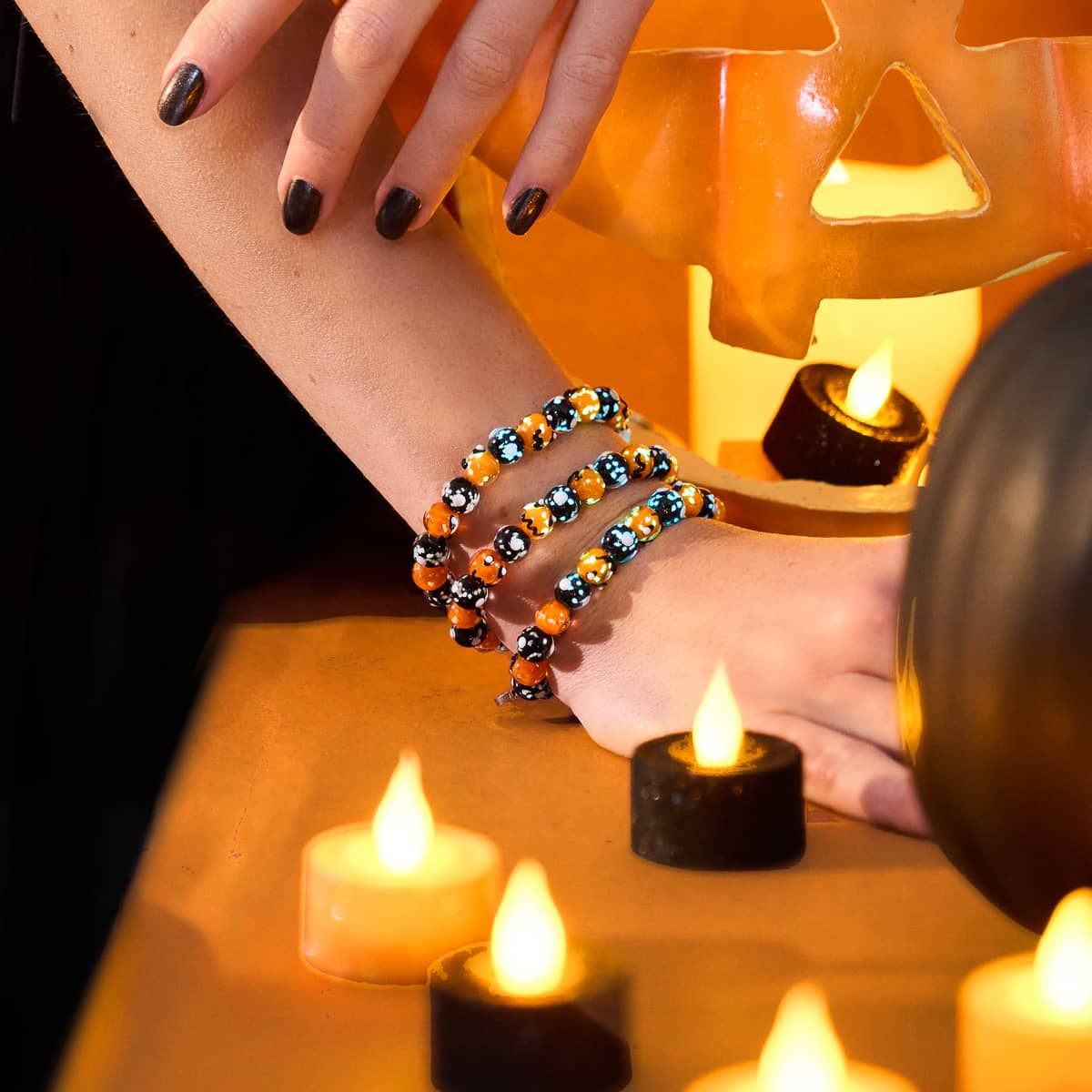 ハロウィンの飾り付けの近くで手首に着ける、オレンジと黒の光るFirefly GlassビーズがついたミッドナイトパンプキンブレスレットNOGU