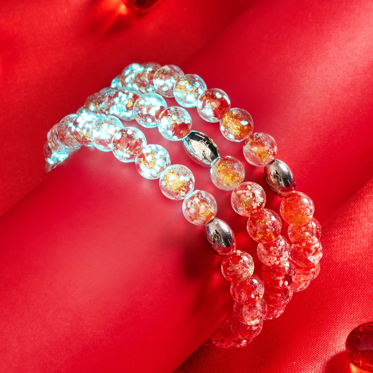 『In Love』Firework Glass、NOGUの赤い生地に銀色の留め具が施された光る青と赤のビーズのブレスレット
