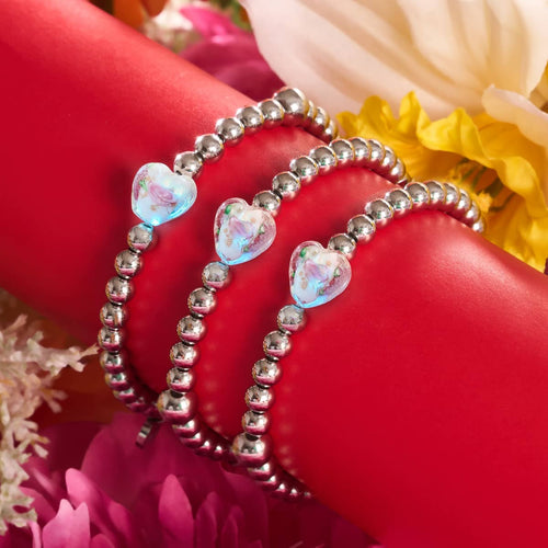 マグノリアの輝くハートのエッセンスブレスレットは銀のビーズと、NOGUの花があしらわれた赤い台に飾られています。