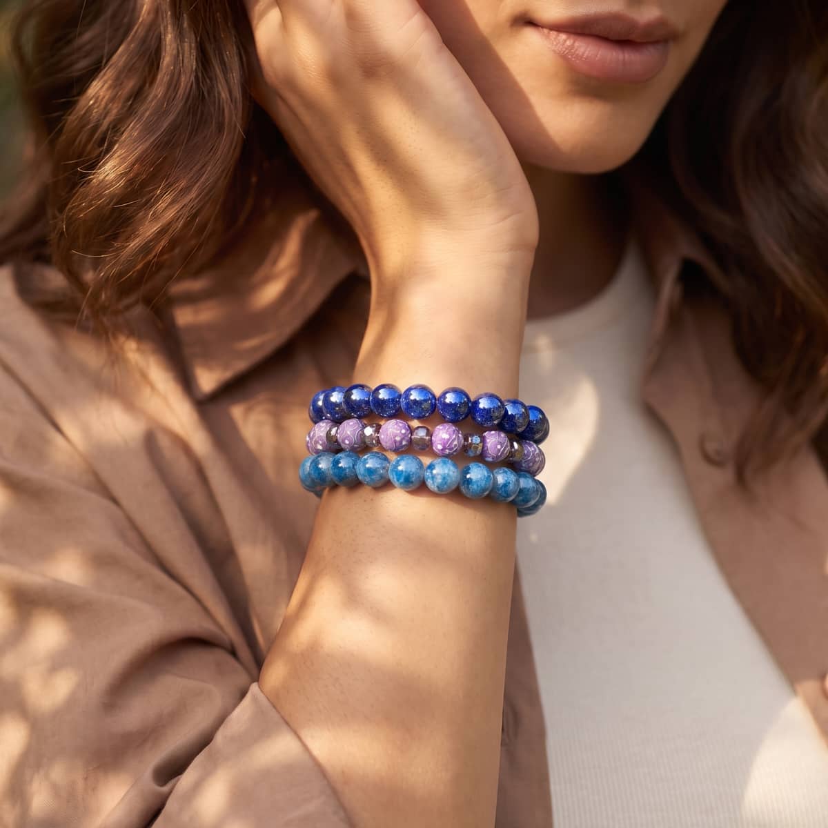 Stack of blue and lavender beaded stretch bracelets with small gold-tone spacer beads, worn on the wrist.