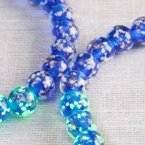 Sapphire Firefly Glass bracelet with cobalt blue lampwork beads, white flecks, gold shimmer, and a luminous green glow.