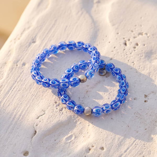 Mediterranean Wave Firefly Glass Tide bracelet with blue and white lampwork beads, silver-tone stainless steel accents and clear stretch cord.