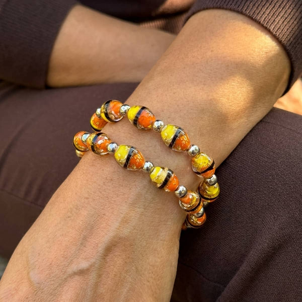 Golden Shore Tiger Glass oval bracelet with orange and yellow striped glass beads, silver accents, and clear elastic cord.