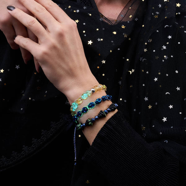 Sunset Spectre Firefly Glass skull bracelet with glowing blue and yellow beads worn on wrist with star pattern fabric by NOGU