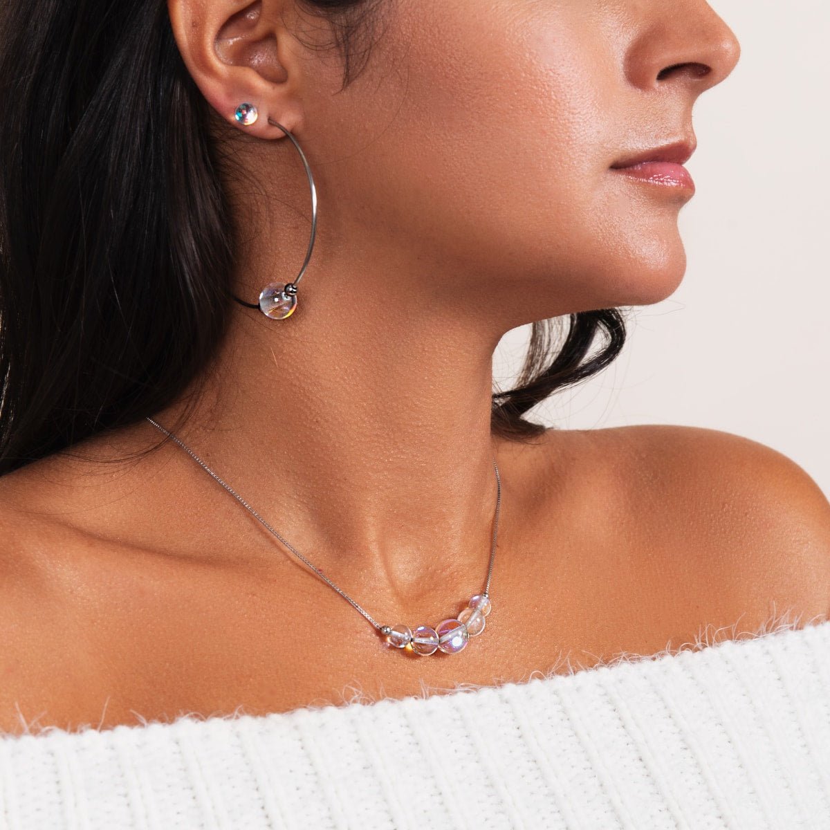 A woman wearing a Rainbow Supernova Galaxy Glass necklace with iridescent beads.