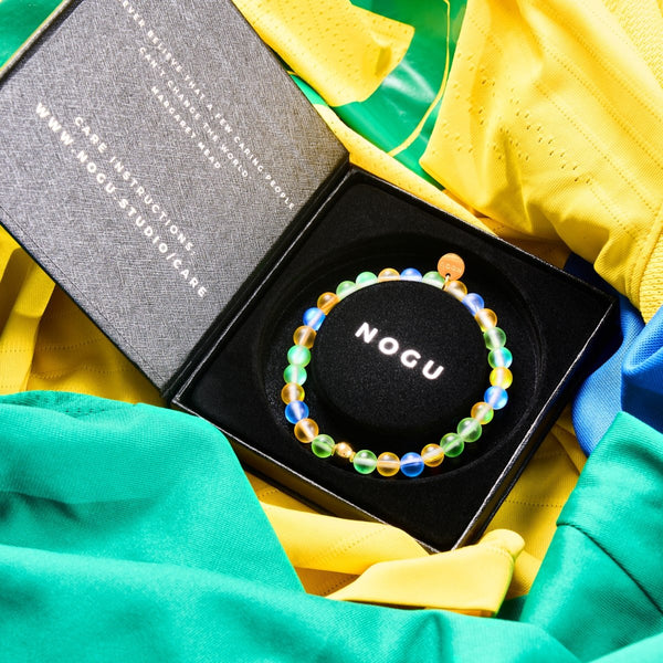 NOGUのブラジルMermaid Glassネイションズ ブレスレットは、6mmの虹色ビーズと金色のステンレスチャームが入った黒い箱にカラフルな生地に入っています