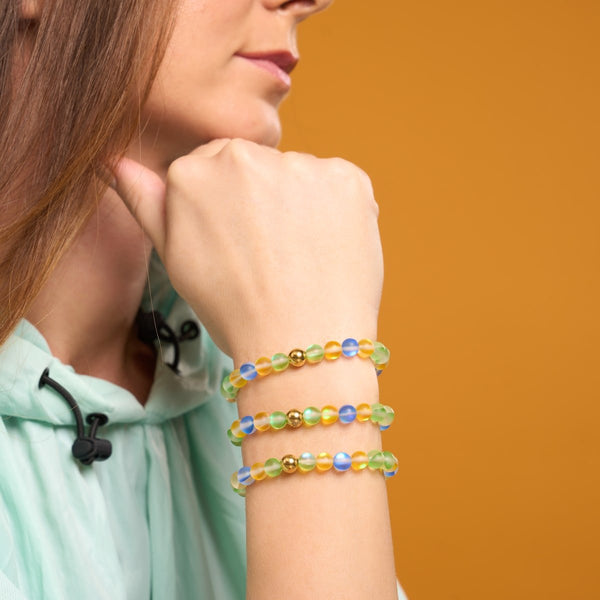 BRAZIL Mermaid Glass Nations Bracelet with 6mm iridescent beads and gold stainless steel charm worn on wrist by NOGU
