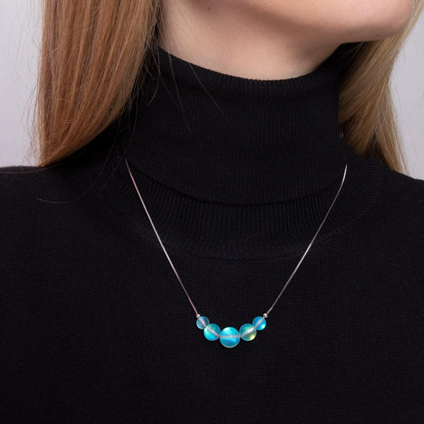 Aquamarine mermaid glass necklace with iridescent beads on sterling silver chain worn with black turtleneck by NOGU