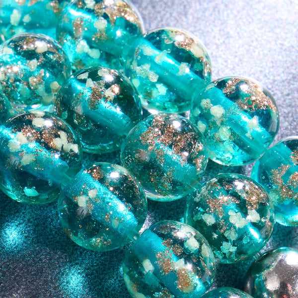 Close-up of teal Firefly Glass beads with silver flecks and .925 sterling silver bead by NOGU